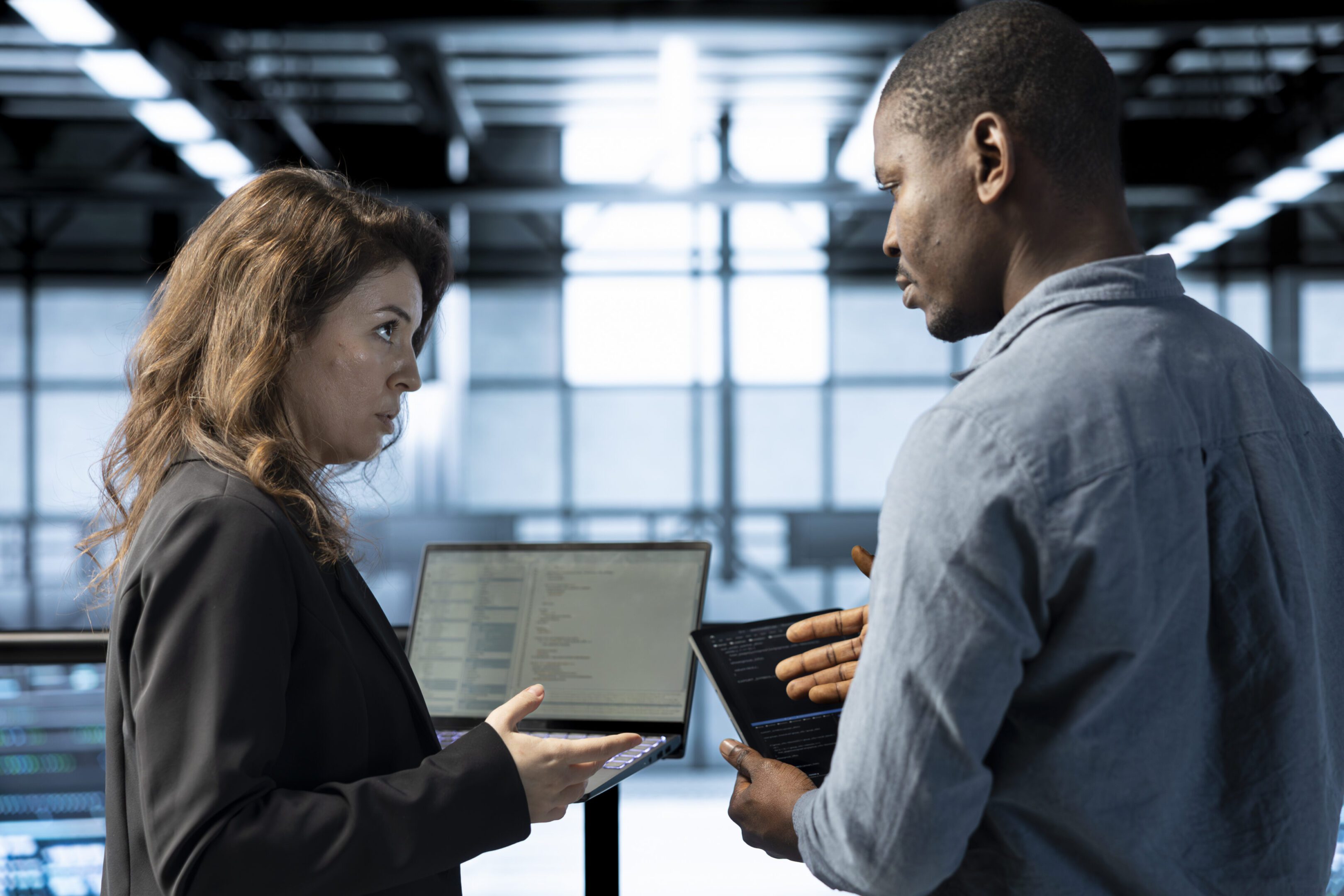 Engineers in data center using devices, employing machine learning models, analyzing historical usage patterns, predicting future infrastructure needs, allocating resources efficiently